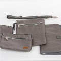 Gray folded padded changing pad and insulated bottle holder bag with zipper closure and wet bag with zipper closures and clutch purse with with zipper closures and with a detachable crossbody messenger strap